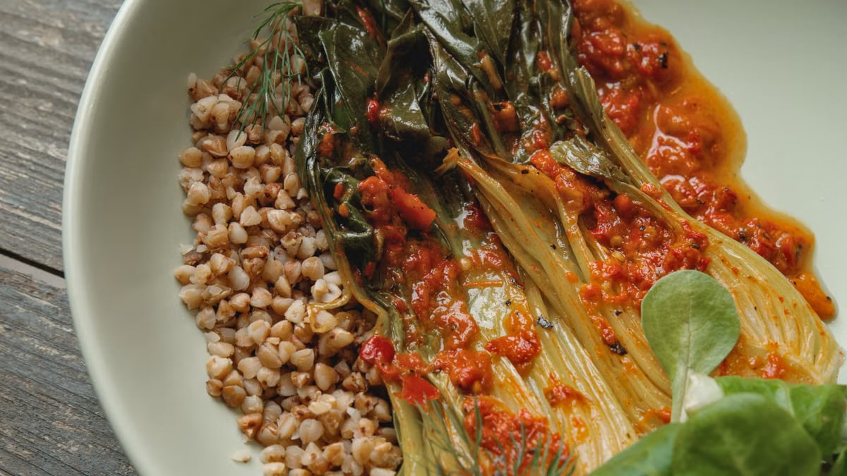 Appetizing dish of grains, greens, and spicy kimchi on rustic tableware.